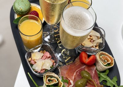 Verwenbordje met bubbels, fruitsap, ham, wraps en aardbeien uit het Total Care-arrangement