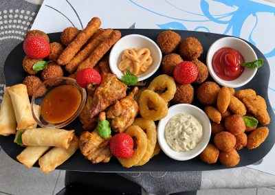 Schotel met warme fingerfood, loempia's, kroketjes, calamares en sausjes
