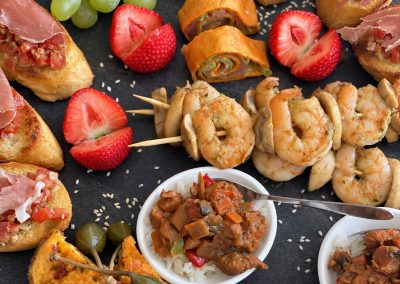 Tapasschotel met wraps, bruschetta met ham, scampispiesjes, fruit en warme hapjes